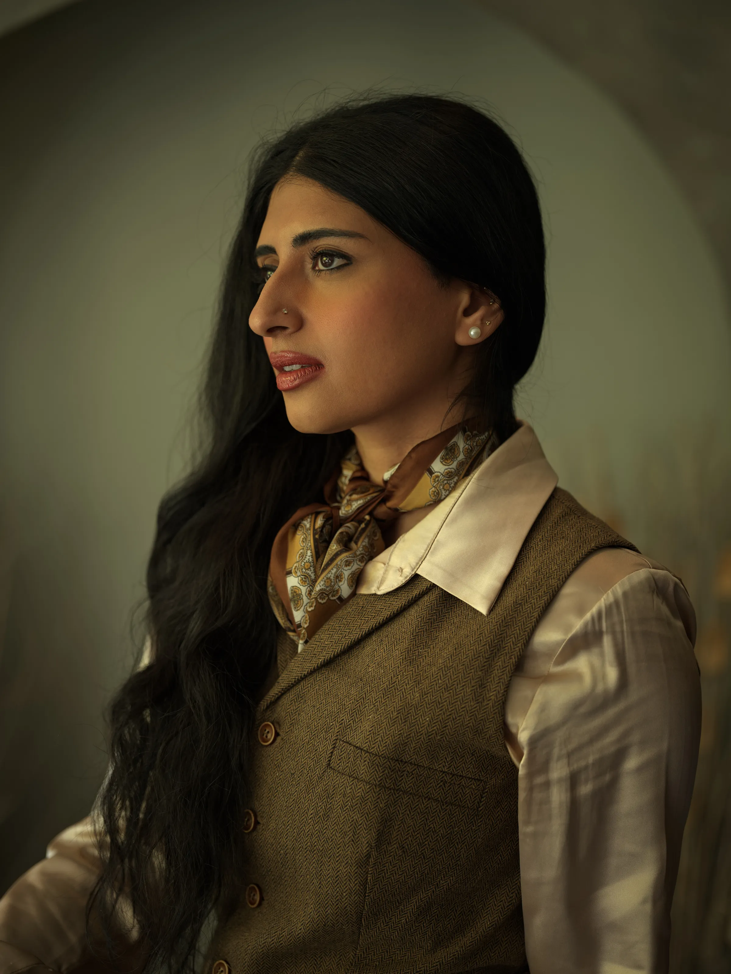 Woman with long dark hair in a herringbone vest and paisley scarf.